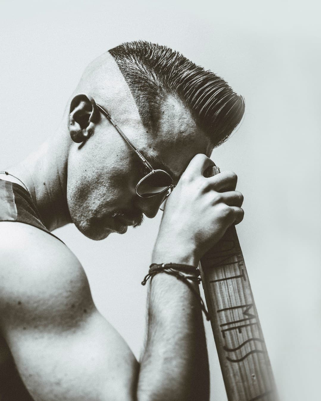 Black and white portrait — high pompadour fade, looking down, sunglasses