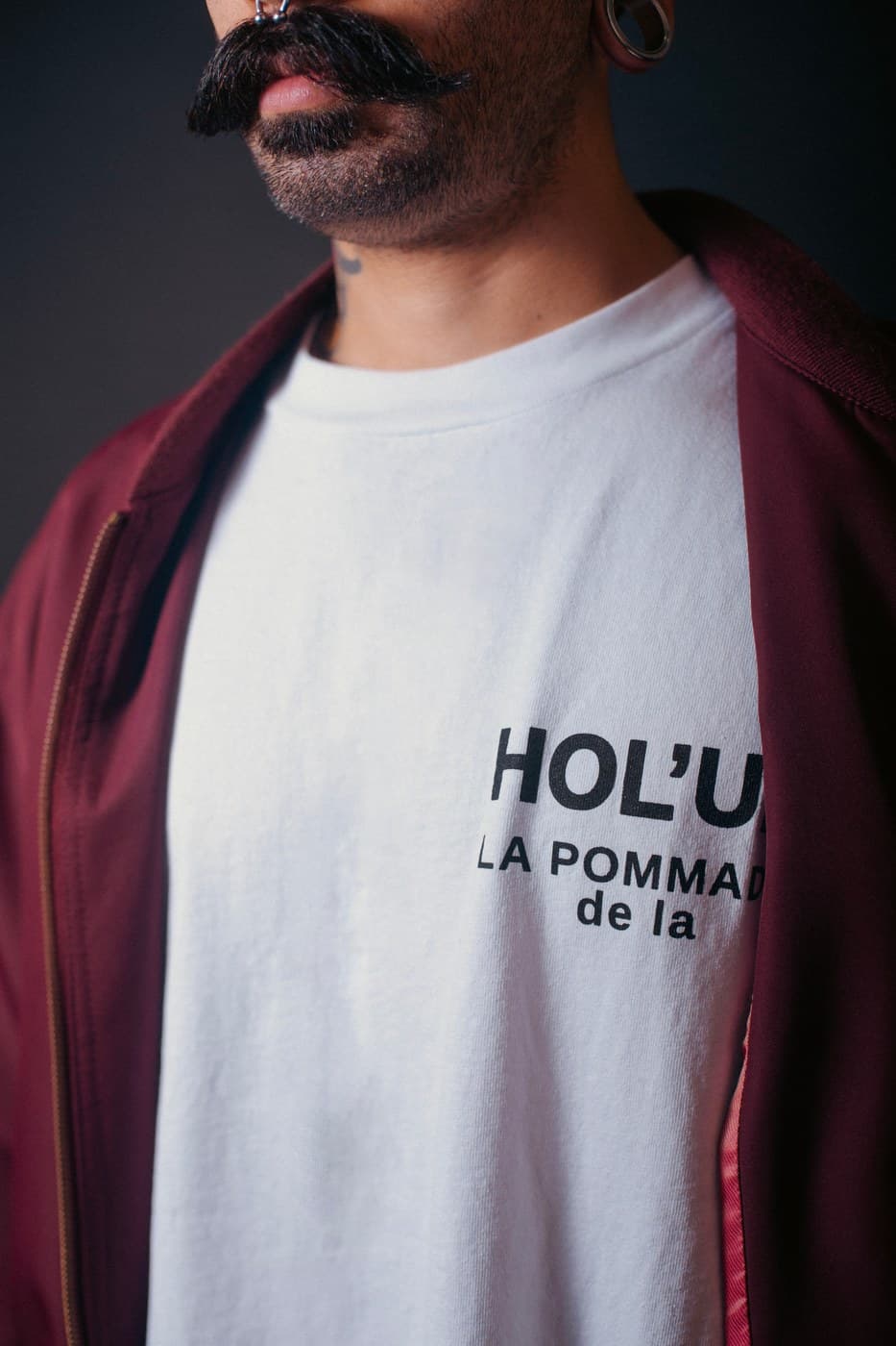 Close portrait of man wearing HOL'UP branded t-shirt, impressive waxed mustache