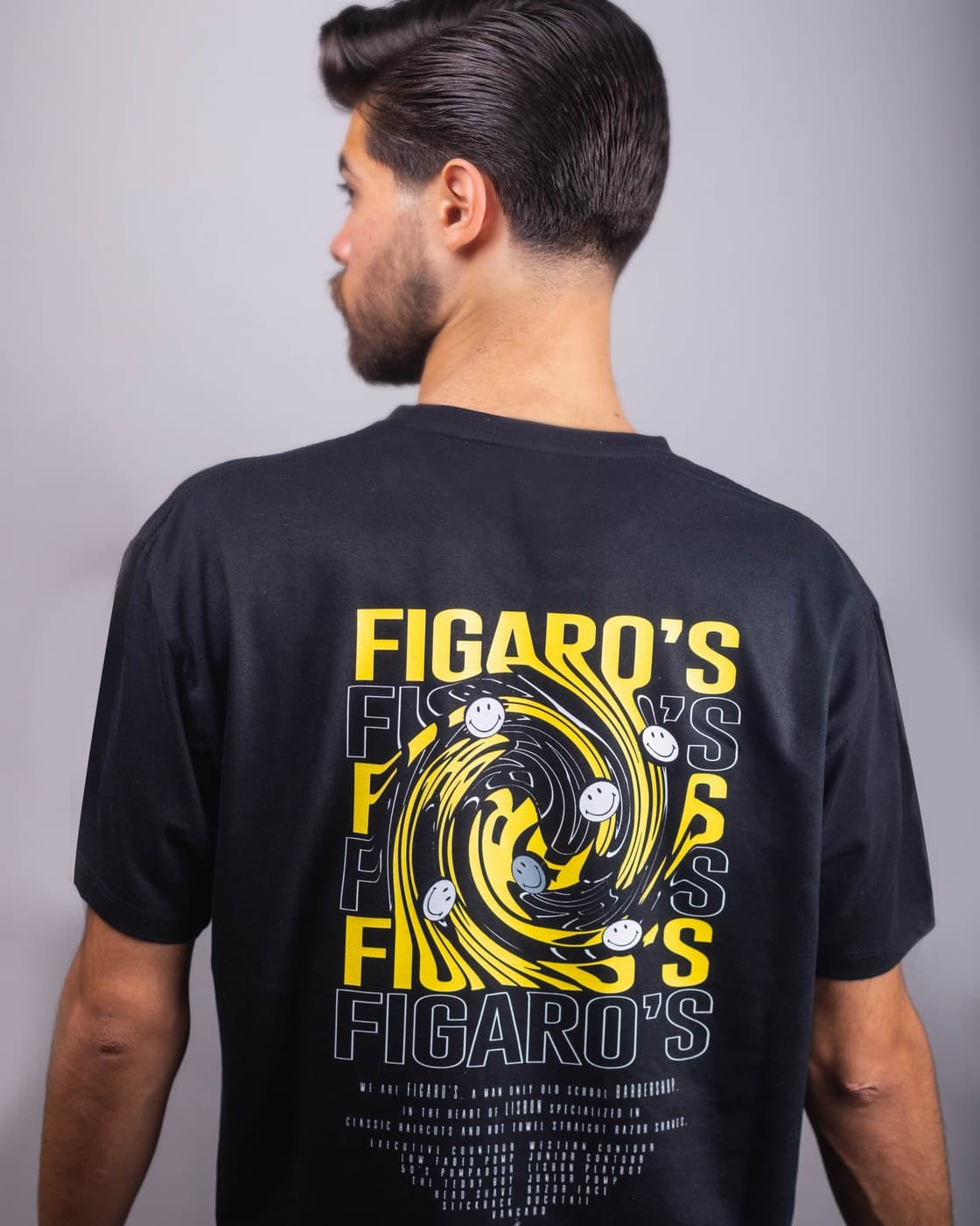 Model wearing Figaro's Barbershop branded t-shirt back view, barbershop setting