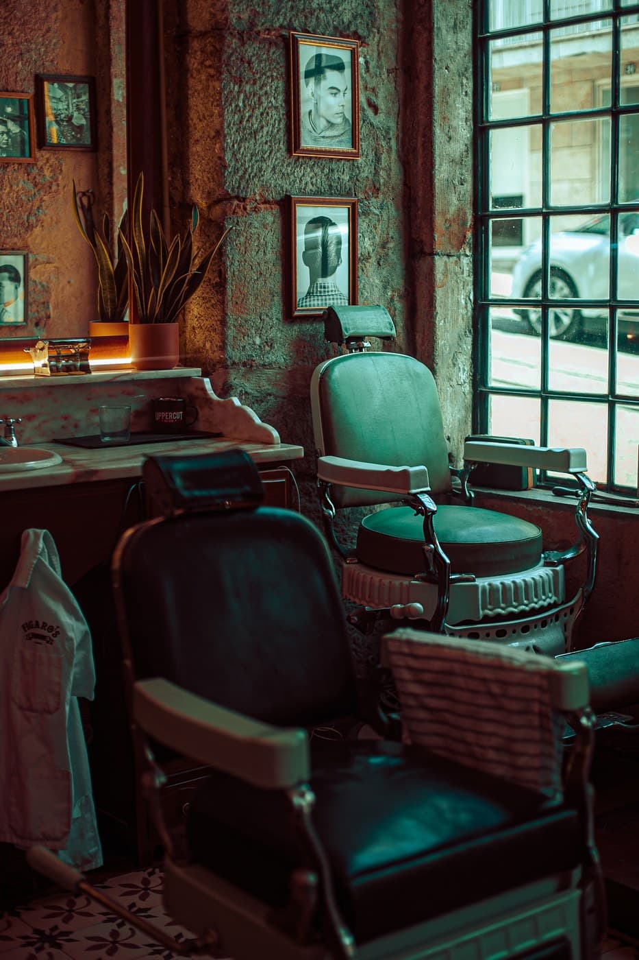 Moody barbershop interior — vintage barber chairs, warm window light and plant