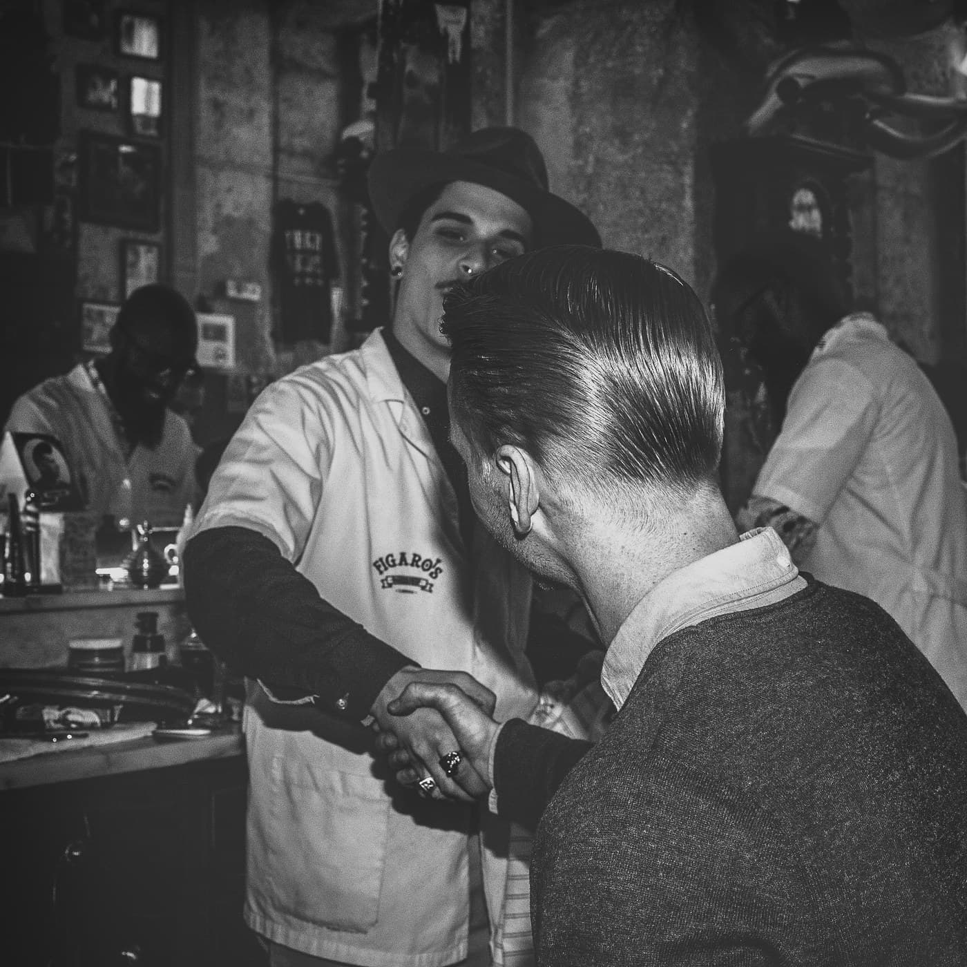 Black and white square — Figaro's barber grooming pompadour from behind
