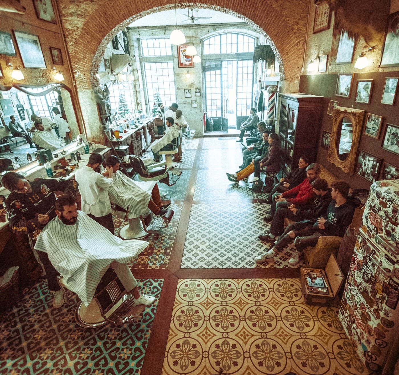 Bird's-eye view of packed Figaro's Barbershop — barbers, clients, waiting area