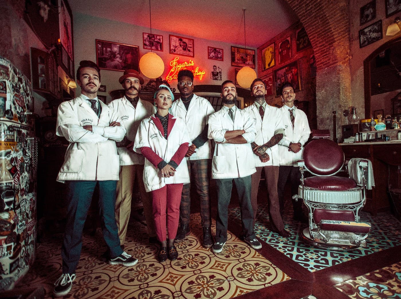 Figaro's Barbershop team in white coats under neon sign, arms crossed