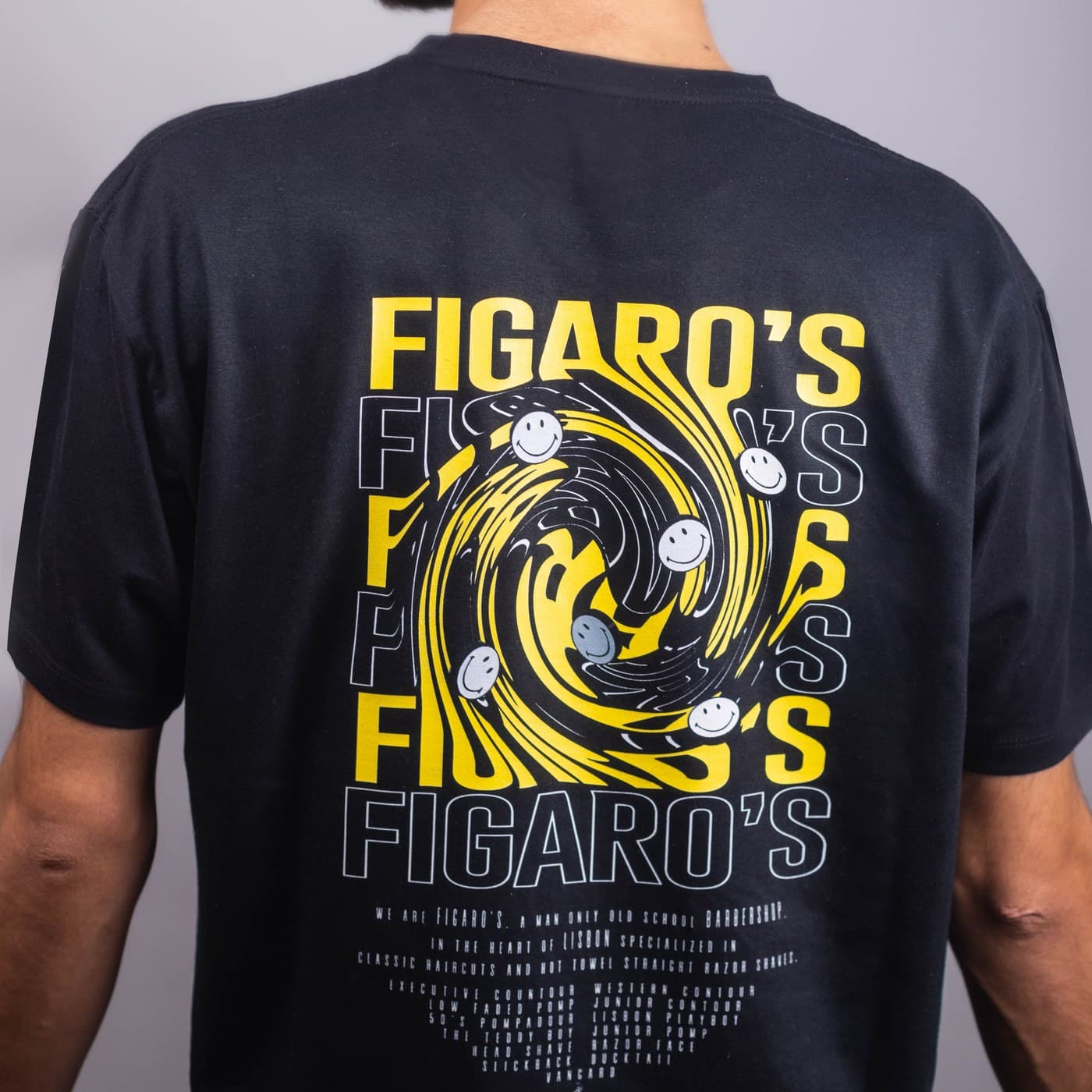 Figaro's Barbershop branded t-shirt back detail — yellow swirl graphic