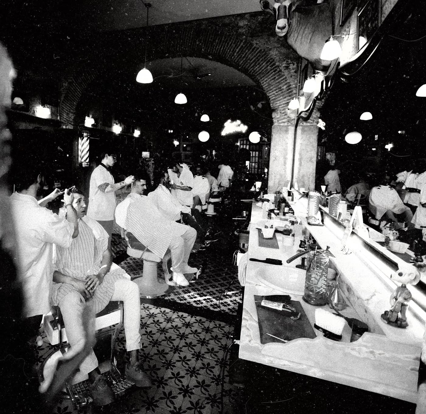 Black and white grainy film square — full Figaro's barbershop interior at night