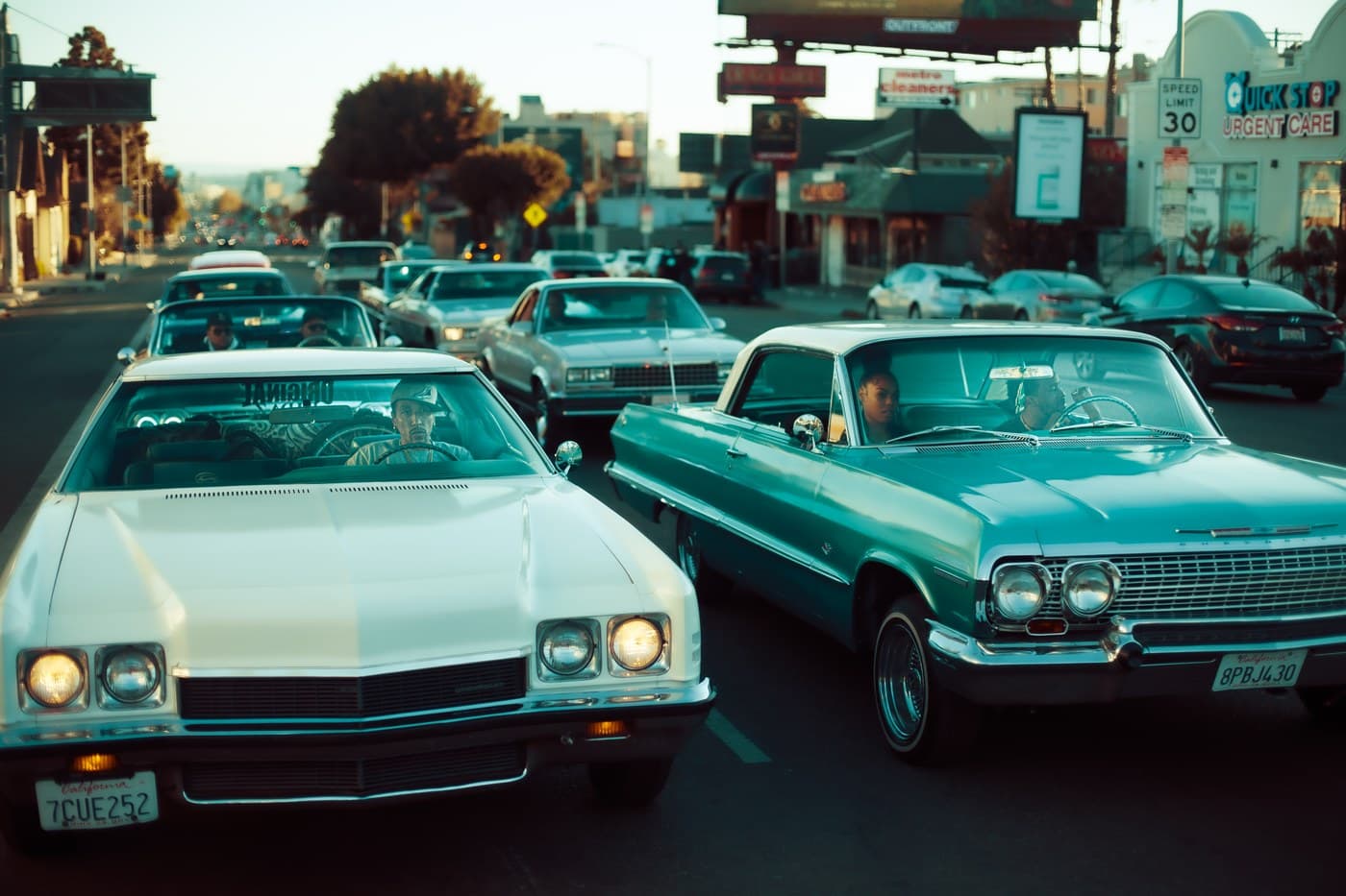 Lowrider Impalas driving through Los Angeles at dusk